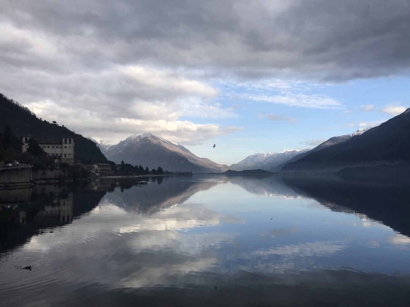 Still winter morning on Lake Como with mountains mirrored in the water